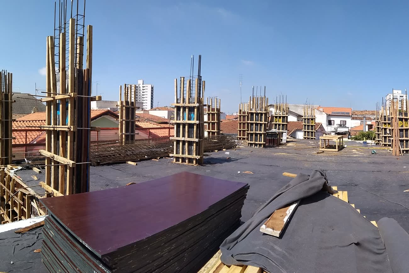 Conjunto de pilares em forma de madeira, travados e escorados sobre a laje