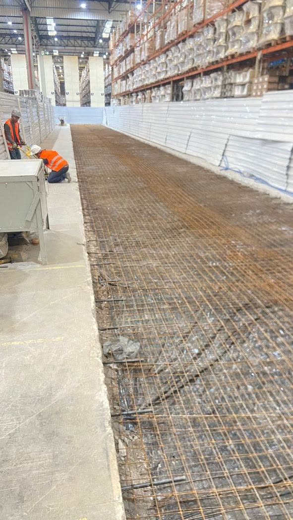 Malha dupla de aço posicionada sobre base preparada para piso industrial em concreto armado